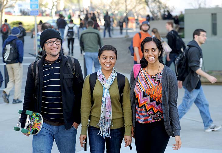 Diverse group of Berkeley students smile as they walk through campus
