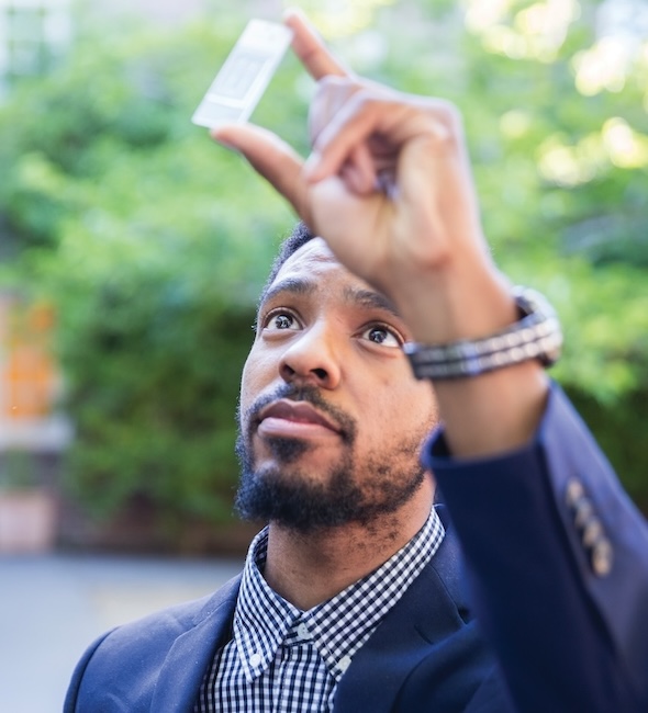 Young man in a suit looking through a cell slide.