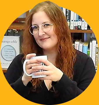 Graduate Tracy Locken holding a mug in front of a bookshelf