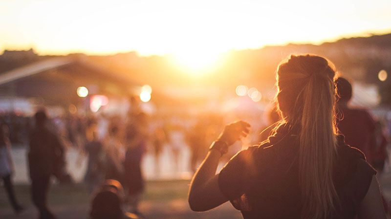 Woman looks out at the sunset while surrounded by her peers