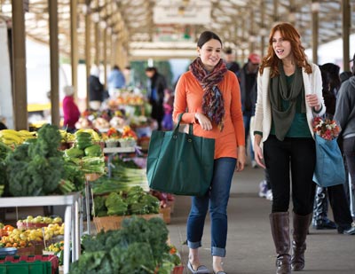 Berkeley students walkin at an open-air produce market holding bags of groceries