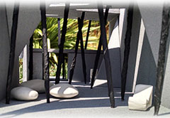 Architectural drawing of an outdoor seating area with cushions, palm-trees, and black, angled, spear-looking support columns.